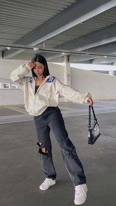 a woman standing in an empty parking garage holding a purse and talking on the phone