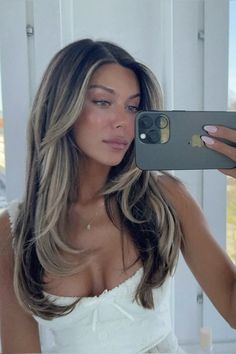 a woman taking a selfie with her cell phone in front of her face and wearing a white dress