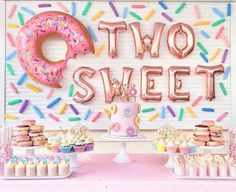 a table topped with donuts and cupcakes next to a sign that says two sweet