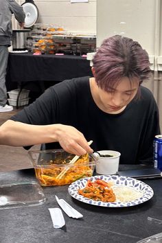 a man sitting at a table with food in front of him and eating out of a bowl