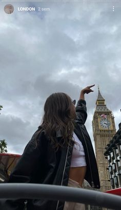 a woman pointing at the big ben clock tower