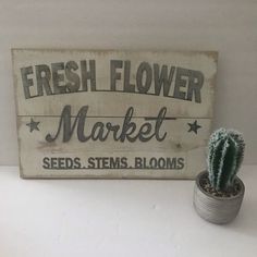 a wooden sign that says fresh flower market seeds stems blooms and a cactus in a pot