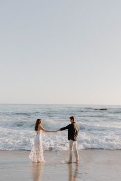 a man and woman holding hands on the beach