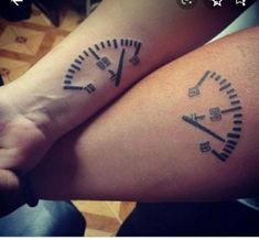 two people with tattoos on their arms holding hands and one has a clock tattooed on the arm