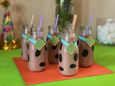 four chocolate milkshakes with purple straws and polka dots on them are lined up in mason jars