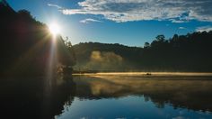 the sun shines brightly over a calm lake