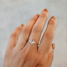 a woman's hand with an engagement ring on her left and the other hand holding it