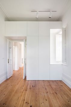 an empty room with white walls and wood floors