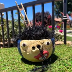 a planter that has been painted to look like a man's head with black hair