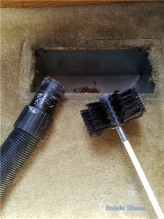 two black brushes laying on top of a carpeted floor next to a hole in the wall