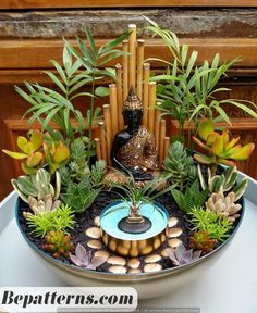 a bowl filled with lots of plants and buddha figurines on top of it