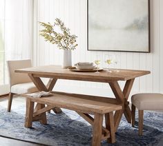 a dining room table with two benches in front of it and a painting on the wall