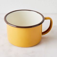 a yellow and brown mug sitting on top of a white counter