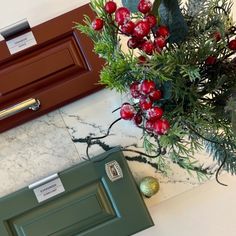 a green box sitting on top of a marble floor next to a christmas tree branch