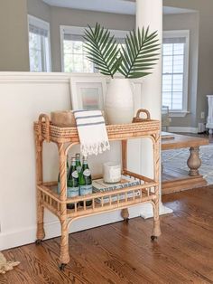 a wicker serving cart with drinks on it in front of a mirror and window