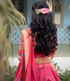 a woman with long black hair wearing a pink sari and flower in her hair