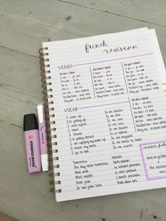 a hand holding a pen next to a notebook with french words on it and an eraser