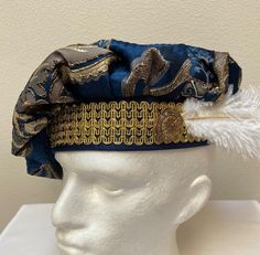 A new adult professional quality Renaissance Medieval Tudor muffin poet floppy hat. This blue and gold brocade hat is embellished with a gold trim band and a white ostrich feather.  Inside lining. New not worn. A great accent for your Medieval Renaissance outfit for your reenactment event, theme party or stage production. Sales final. Will exchange for a different size. Size X small has a 21 1/2" band Size small has a 22" band Size medium has a 22 1/2" band Size large has a 23" band Size X large Blue Costume Hat For Carnival, Gold Mardi Gras Costume Hats And Headpieces, Traditional Costume Hats And Headpieces For Carnival, Blue Carnival Costume Accessories, Gold Costume Hats With Round Crown, High Crown Costume Hat For Mardi Gras, High Crown Costume Hats And Headpieces For Mardi Gras, Mardi Gras Costume Hat With High Crown, Royal Knight