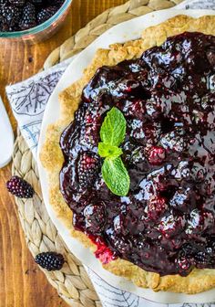 a pie with blueberry sauce and fresh mint garnish sits on a woven placemat