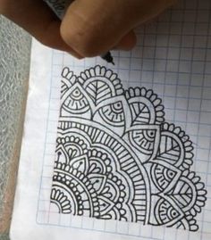 someone holding a pen and drawing on paper with an intricate design in the middle of it