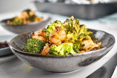 a bowl filled with broccoli and shrimp on top of a white countertop