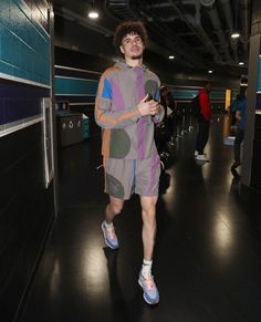 a young man is walking down the hall in shorts and an oversize sweatshirt with his hands on his hips