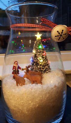 a glass vase filled with snow and christmas decorations