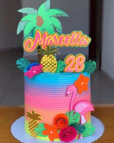 a colorful cake decorated with pineapples, flamingos and palm trees is on a table