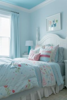 a white bed sitting in a bedroom next to a window with blue paint on the walls