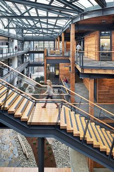 a person walking down some stairs in a building with lots of wood and metal railings