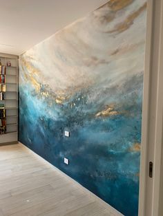 a room with a large painting on the wall next to a book shelf filled with books