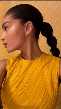 a woman in a yellow dress holding a wine glass and looking off into the distance