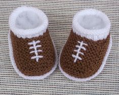 a pair of brown and white crocheted baby shoes on top of a blanket