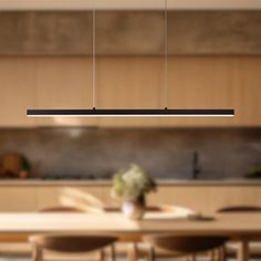 a dining room table and chairs in front of a kitchen with an island light hanging over it