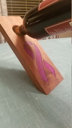 a bottle of wine is being poured into a wooden block with pink paint on it