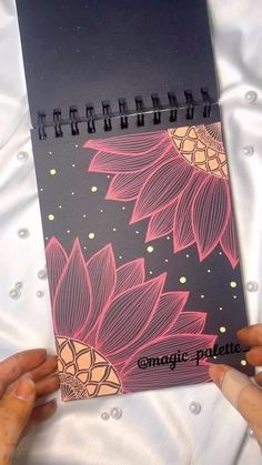 two hands holding up a spiral notebook with flowers on it