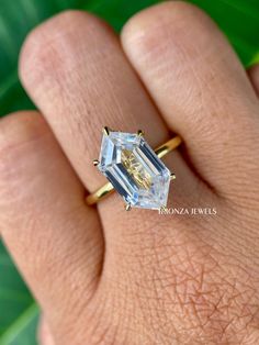 a woman's hand with a ring on it and an emerald colored diamond in the middle