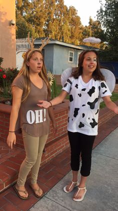 two women dressed up as cowgirls standing next to each other on the sidewalk