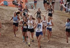 a group of girls running in a cross country race