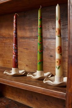 three candles sitting on top of a wooden shelf