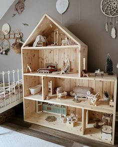 a wooden doll house sitting on top of a bed next to a white crib