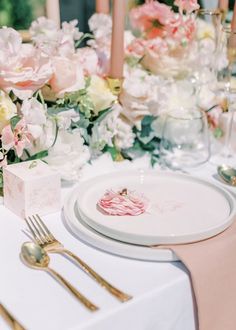 the table is set with pink and white flowers, silverware, and napkins