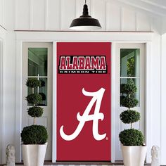 the front door of a house with two potted plants and a large university logo on it