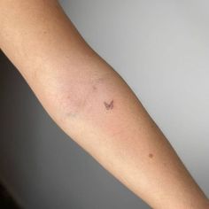 a woman's arm with a small butterfly tattoo on the left forearm and right arm