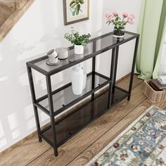 a black table with two vases and flowers on it next to a stair case