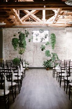 an empty room with chairs and plants on the wall behind them is set up for a wedding ceremony