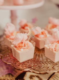 small desserts are arranged on a glass platter with pink icing and star decorations