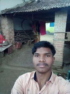 a man standing in front of a brick building with a straw hut on the roof