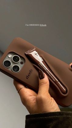 a person holding an iphone 11 pro in their left hand with the case open and two pens sticking out of it