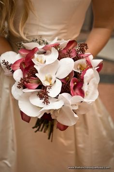 a bride holding a bouquet of white and red flowers